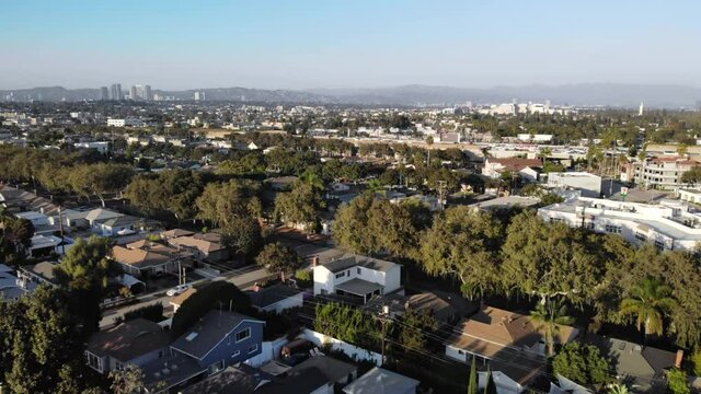 Aerial flyover over streets and neighborhood houses towards interstate 405, Los Angeles suburbs, in California, USA, Sunset, drone shot