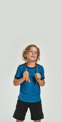 Naklejka premium Happy little sportive boy child in sportswear smiling aside while posing, standing with jump rope isolated over white background