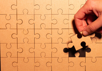 Close up and top view of woman putting the last piece into a puzzle.