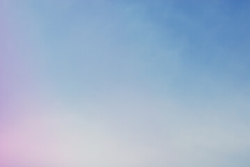 Soft pink purple cloud illuminated by golden light over blue sky background in twilight time. Empty natural sky with pastel tone colors for background or wallpaper.
