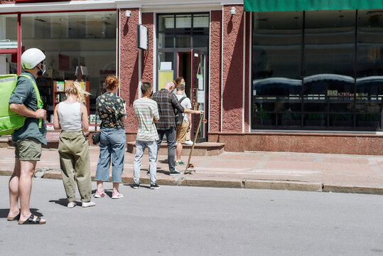 Full Length Shot Of People Waiting, Standing In Line, Respecting Social Distancing To Collect Their Orders, Purchases From The Pickup Point During Coronavirus Lockdown