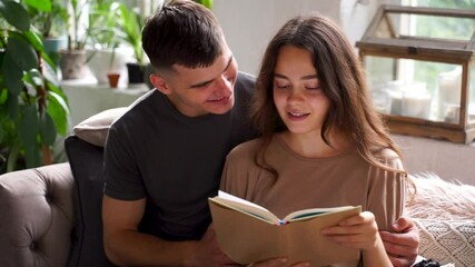 Young lovers woman and man read a book together. Romantic couple at home. 