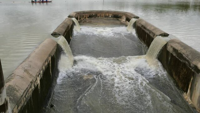Turbid water in the dam overflows into the spillway, Irrigation during the rainy season, People rowing in the dam in Thailand	