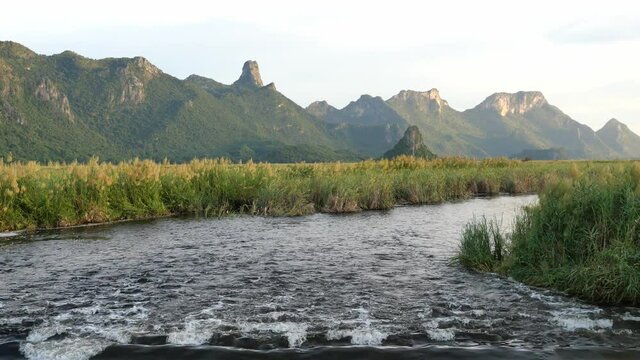 Rock cliff and green forest in lake with blue sky and white could in background, Limestone mountain with water flowing of the vast wetland at Khao Sam Roi Yot National Park , Thailand