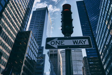One Way banner under the traffic lights with modern skyscrapers in the background