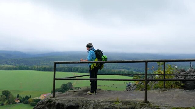 Frau betritt beim Wandern in der s&auml;chsischen Schweiz einen Aussichtspunkt auf dem Papststein bei regnerischem Wetter und ein paar Tauben fliegen davon