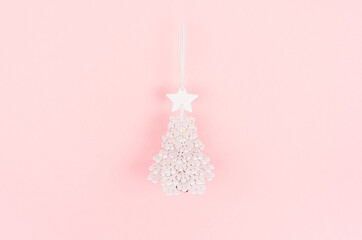 Christmas festive background with white carved wood decoration - christmas tree on pink backdrop, flat lay.