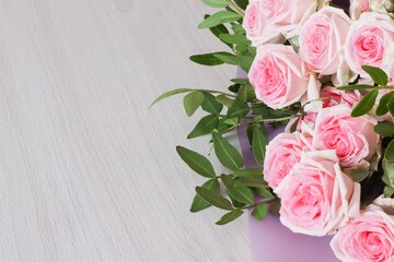 White and pink rose flowers bouquet on white wooden background with space for text. Top view.