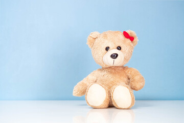 Teddy Bear sitting on a white table and blue background.