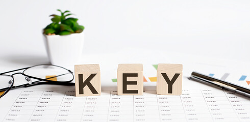 KEY word concept written on wooden blocks, cubes on a light table with flower ,pen and glasses on...