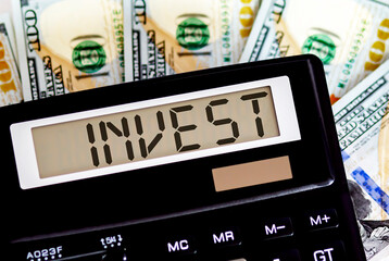 Calculator with text INVEST on the dollars. Business, finance conceptual.