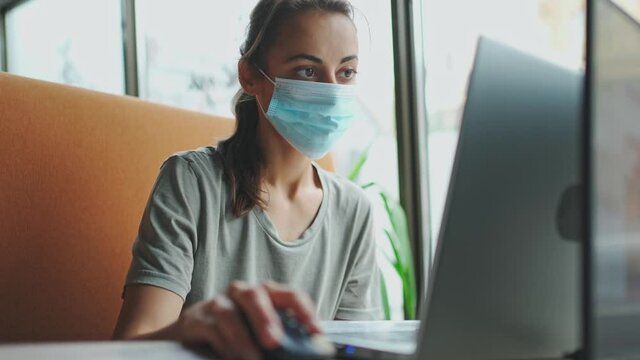 young woman freelancer tired of wearing a mask on her face, takes it off and breathes in with relief. covid-19 quarantine and preventive measures
