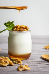 Primer plano de iogurt con miel donde la miel va cayendo encima de las nueces