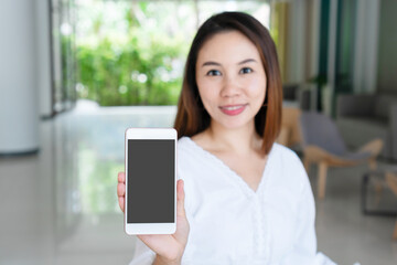 Fototapeta premium Beautiful young Asian girl holding mobile phone for copy space. Technology and lifestyle concept. closeup
