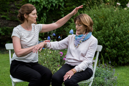 Reiki therapist with a client in a therapy session touching meridian points on the body.
