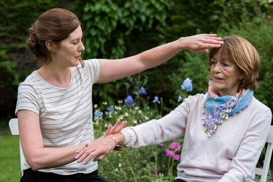 Reiki therapist with a client in a therapy session touching meridian points on the body.