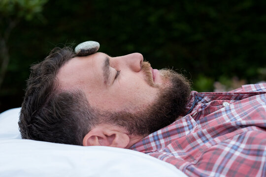 A man on a couch with a stone on his forehead, therapy session. 