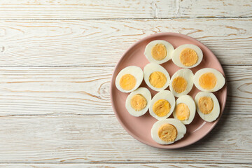 Plate with boiled eggs on white wooden background