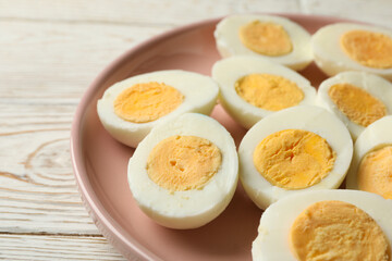 Plate with boiled eggs on white wooden background