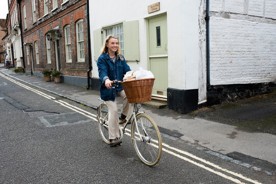 Young blond woman cycling down a village street.