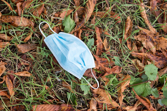 High Angle Close Up Of Disposed Blue Surgical Face Mask Lying On Ground.