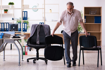 Old male employee doing physical exercises at workplace
