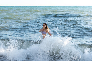 A young girl in a bikini bathing day in a stormy sea.