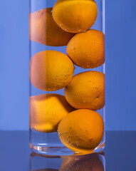 Tangerines in a glass glass with water and gas bubbles.