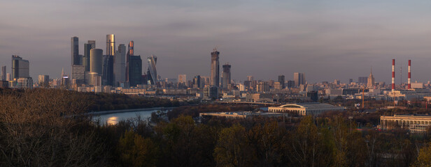 Fototapeta premium Panoramic view from Vorobyevy gory or Sparrow Hills on the Moscow city business center in the autumn evening. It is a modern complex of skyscrapers on the Moskva River embankment. Evening cityscape.