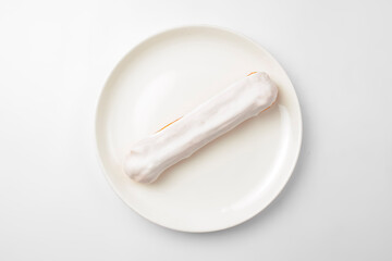 Fototapeta na wymiar White chocolate eclair on plate on white background. Delicious vanilla dessert for tea time.
