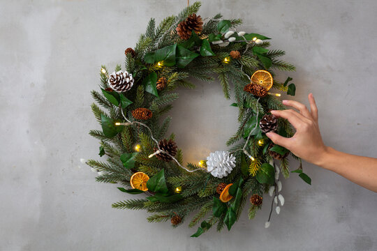 Christmas decorations, close up of person decorating Christmas wreath with ornaments.
