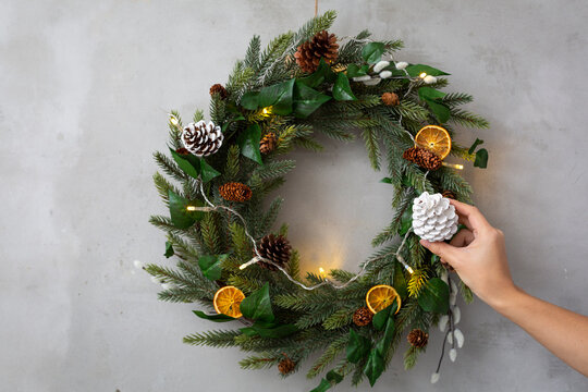 Christmas decorations, close up of person decorating Christmas wreath with ornaments.