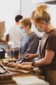 Blond waitress wearing face mask working in a cafe, preparing food.