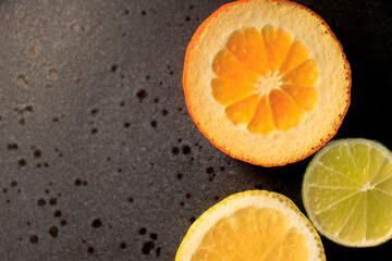 Plate with citrus fresh fruit tangerines with leaves, lemon, lime orange on a dark round plate on a concrete background . vitamins, close-up