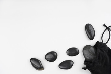 Massage black stones, bag frame on white background. Cosmetology, spa, wellness, self-care concept. Top view, flat lay, copy space