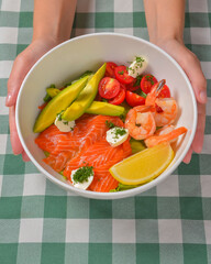 Fresh salad with seafoods, tomato and herbs. Red salmon, small shrimps, avocado, cherry tomatoes.