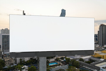 Blank white road billboard with Bangkok cityscape background at sunset. Street advertising poster, mock up, 3D rendering. Front view. The concept of marketing communication to promote or sell idea.