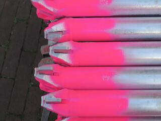ends of the metal pipes of scaffolds painted pink laying on the street