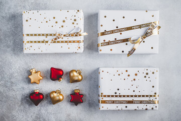 Gift boxes in white paper with stars and dots with golden ribbons on grey background. Christmas and New Year background. 