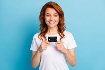 Photo portrait of woman holding credit card with two hands isolated on pastel blue colored background