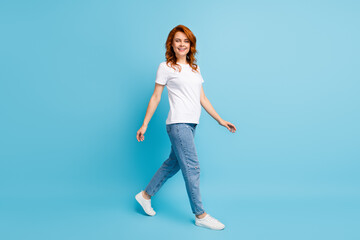 Fototapeta na wymiar Photo portrait full body view of woman walking isolated on pastel blue colored background