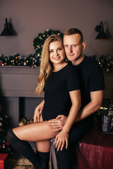 Fototapeta na wymiar Passionate romantic couple spend time together before the New Year near a beautiful Christmas tree at home. Sexy young woman and handsome man hugging and celebrating new year