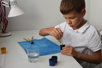 The child draws on a blue sheet with a brush. Hobbies and entertainment at home