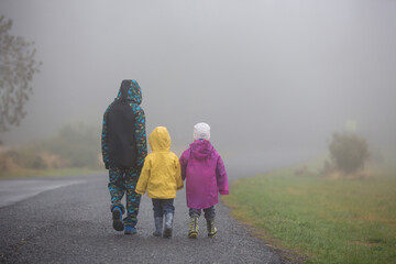 Children, siblings, walking on a rural path on a foggy autumn day