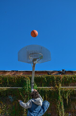 Young man playing basketball jumping towards the basket.