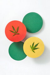 Multicolored round cards with marijuana leaves on a light grey background.