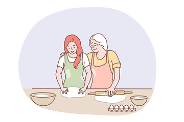 Happy family cooking together concept. Happy elderly grandmother hugging granddaughter and showing how to bake pastry or pie with eggs and dough in kitchen. Baking, family, grandparents help