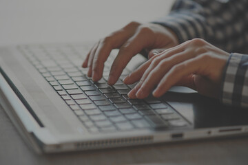 Close-up of female hands typing on the keyboard work process, checkered shirt.