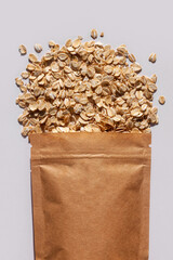 Brown kraft paper pouch bags with oats top view with harsh shadow on white background. Oatmeal cereal porridge pack flat lay. Rolled oat flakes packaging, healthy vegan food template mockup for design