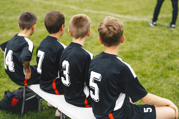 Boys in blask soccer jersey shirts sitting on football bench © matimix